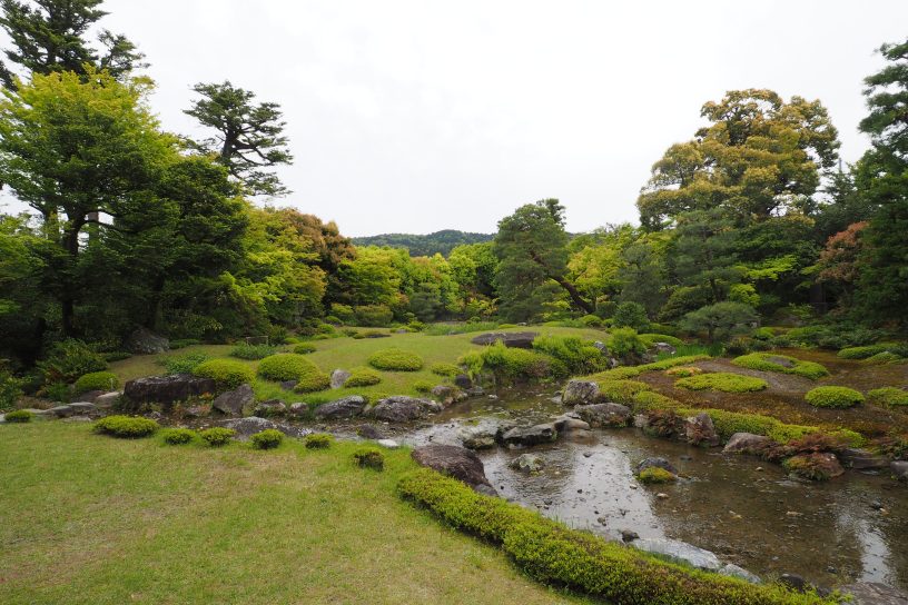 明るい芝生が一面に敷かれた開放的な庭園。奥には東山が見えます。