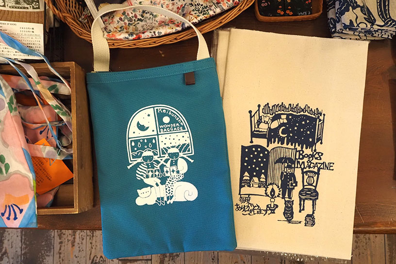 WONDER BAGGAGEとのコラボ商品<br/>
左：バッグ「読書三余」（ひろせべに）4,345円 右：ブックケース「読書三余」（関美穂子）2,310円<br/>
